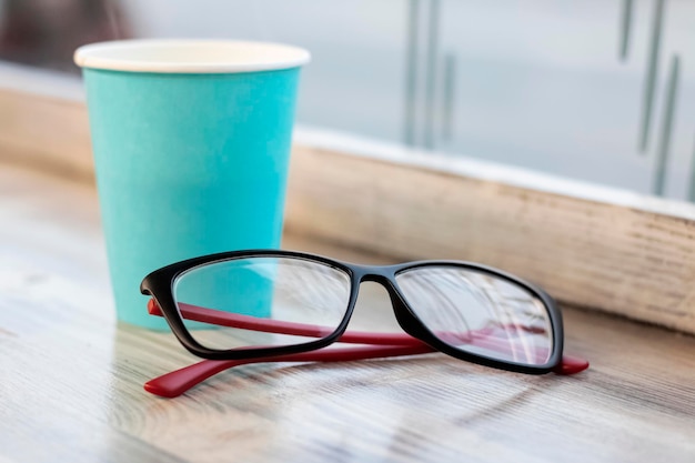 Taza azul con café y vasos en la mesa de madera