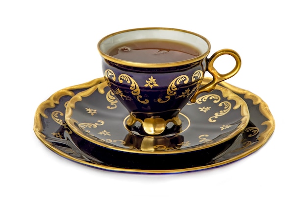 Taza azul dorada con té en un plato con un primer plano de platillo aislado en un fondo blanco. taza con