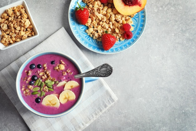 Taza con batido de acai sobre fondo gris