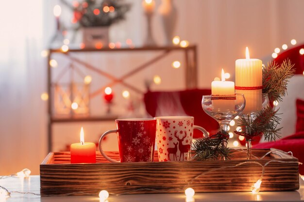 Taza de bebida caliente con adornos navideños en colores blanco y rojo en casa