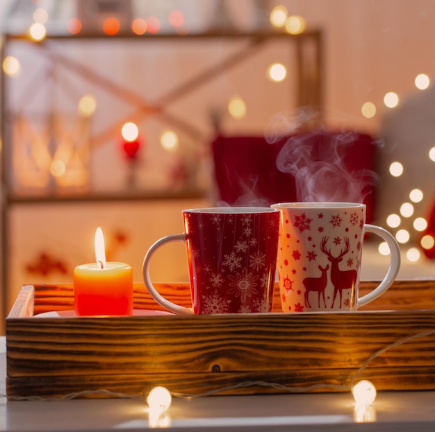 Taza de bebida caliente con adornos navideños en colores blanco y rojo en casa