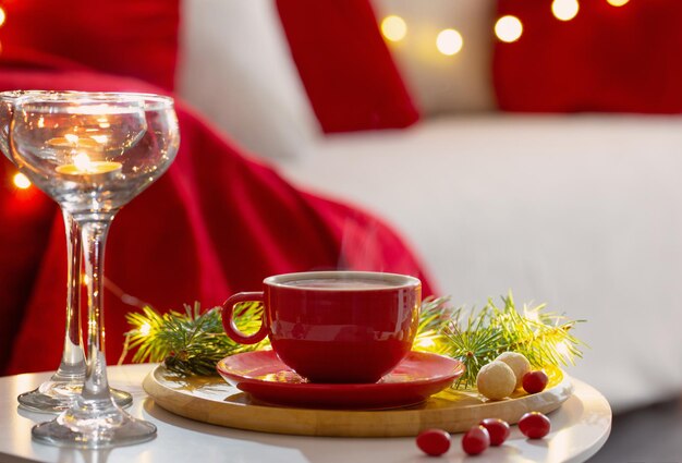 Taza de bebida caliente con adornos navideños en colores blanco y rojo en casa