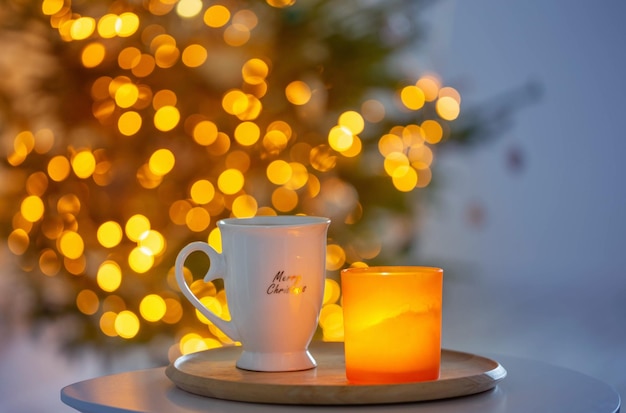 Taza con bebida caliente en el árbol de navidad de fondo