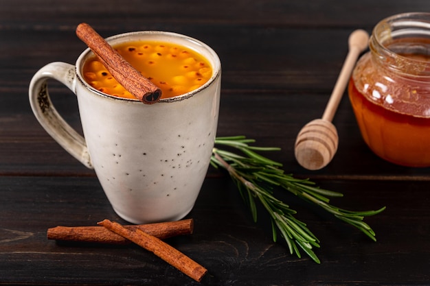 Una taza de bebida caliente de espino cerval de mar sobre fondo de madera oscura.