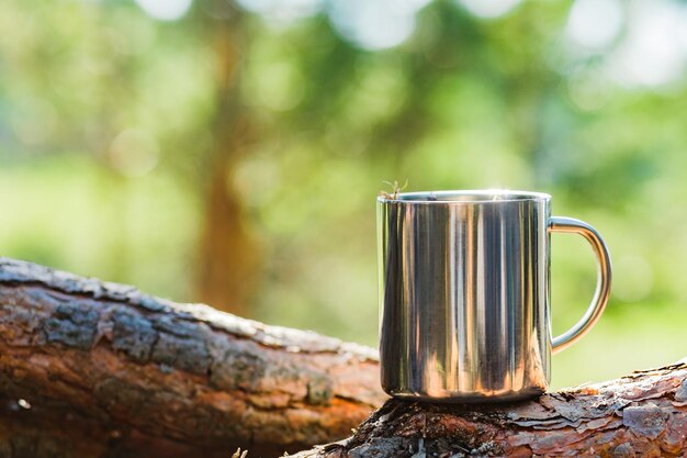 Taza con una bebida caliente en un tocón de madera al aire libre Mañana en el camping