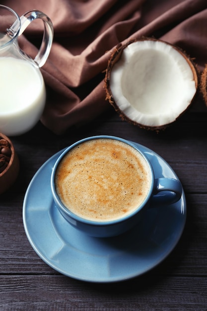 Taza con bebida e ingredientes para café de coco en mesa de madera