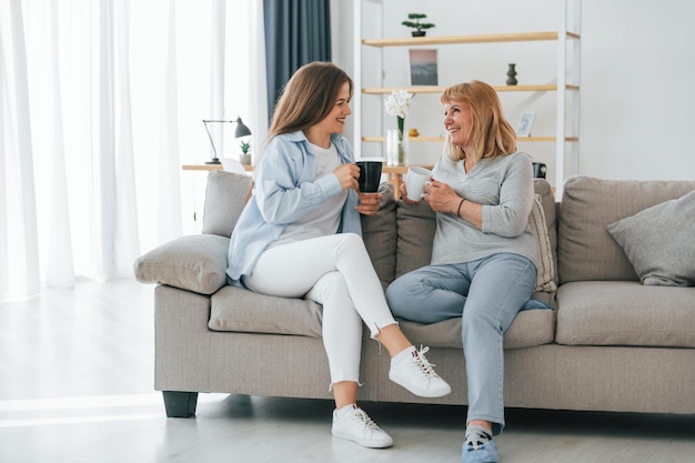 Con una taza de bebidas conversando Madre e hija están juntas en casa