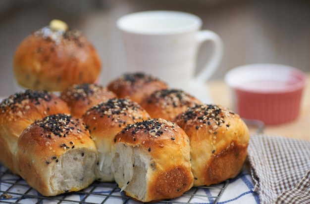 Una taza blanca con un asa está al lado de un bollo de pan.