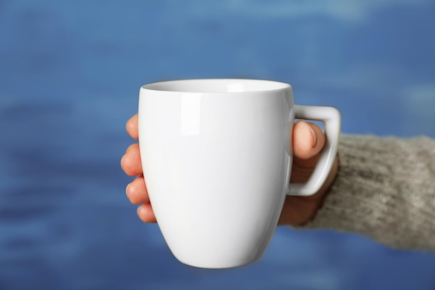 Taza blanca en blanco en primer plano de la mano