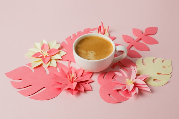 Taza blanca de café espresso sobre un fondo rosa pastel con papel de origami moderno