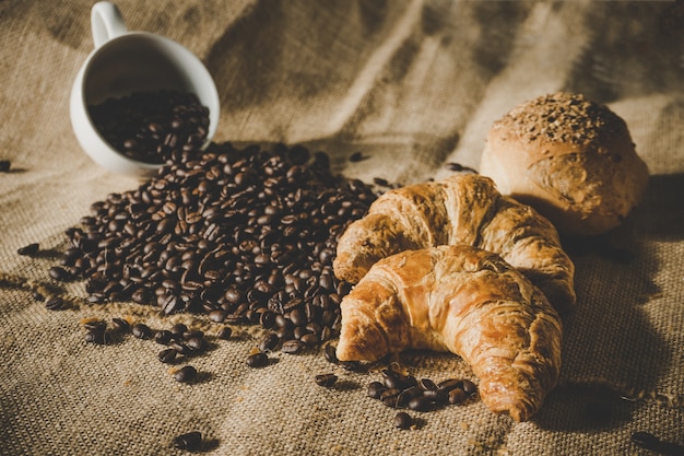 taza blanca de café de frijoles con croissant y pan