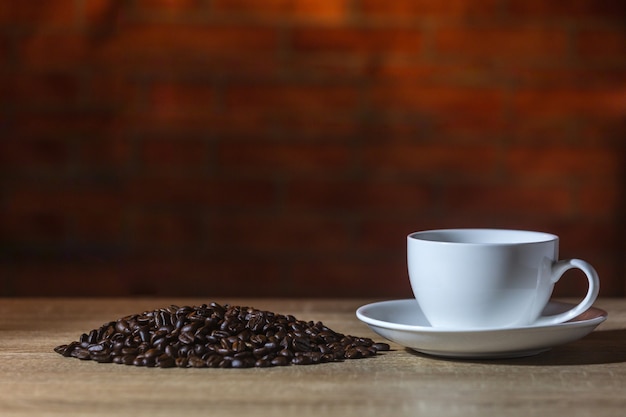 Foto taza blanca de café con leche caliente y grano de café en la mesa de madera