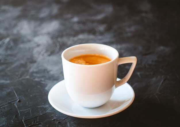 Taza blanca de café con leche en una mesa de pizarra negra