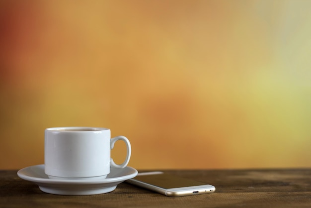 Taza blanca de café con teléfono en colores de fondo con espacio de copia