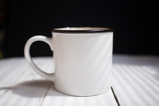 Taza blanca con copia espacio en la mesa blanca.