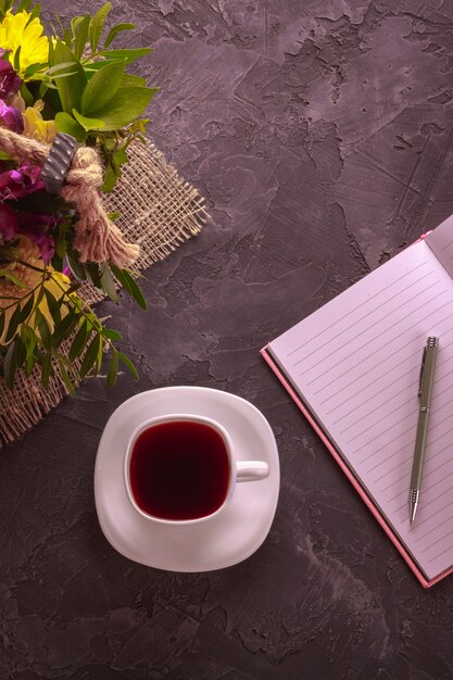 Taza blanca con un cuaderno y flores