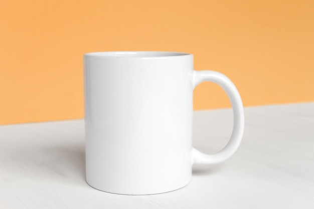 Una taza blanca en el diseño de vista frontal de primer plano de la mesa para el diseño con espacio de copia