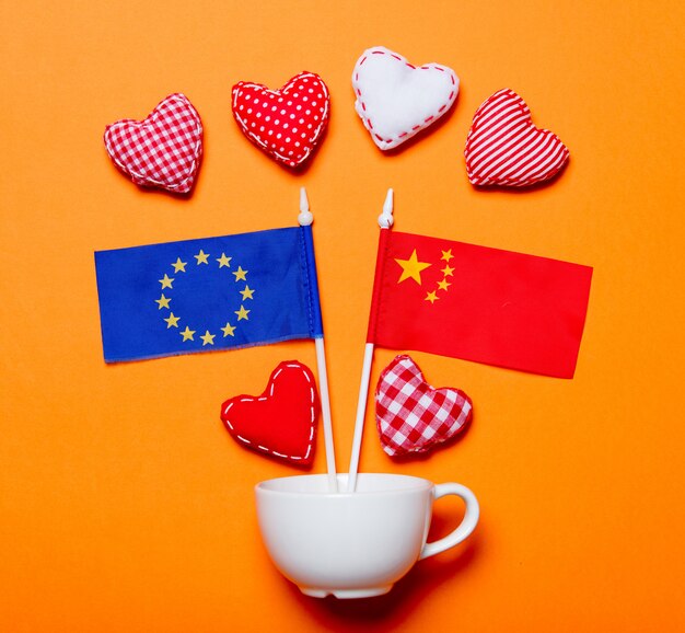 Taza blanca y formas de corazón con banderas de la Unión Europea y China.