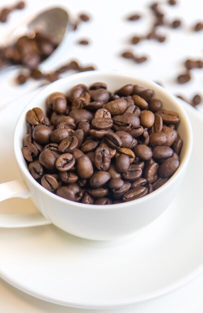 Taza blanca y granos de café sobre un fondo blanco. Enfoque selectivo.