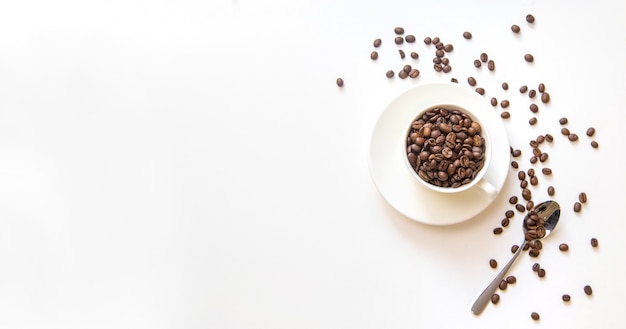 Taza blanca y granos de café sobre un fondo blanco. Enfoque selectivo.