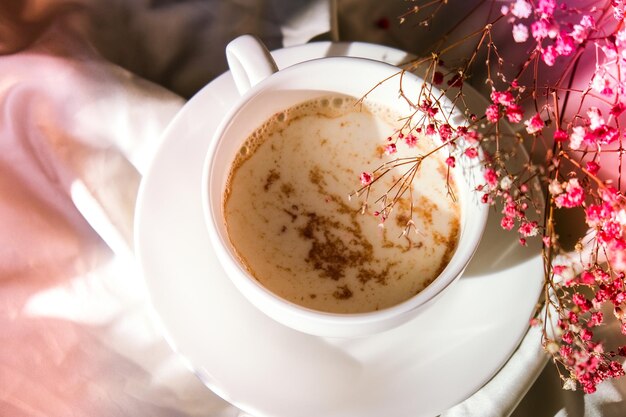 Taza blanca de leche y chocolate. Vibraciones estéticas matutinas. Desayuno. Flores de gipsófila rosa