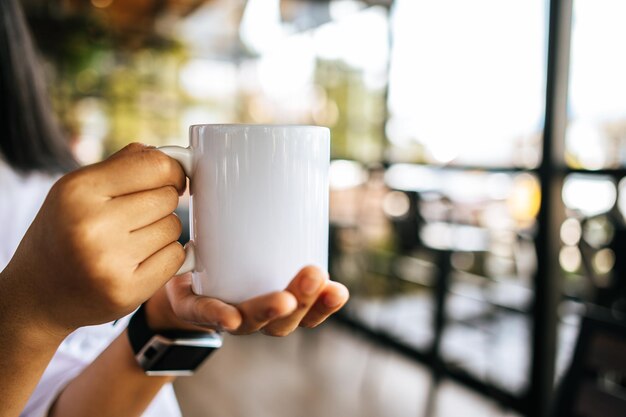 taza blanca a la mano en el tiempo de relajación