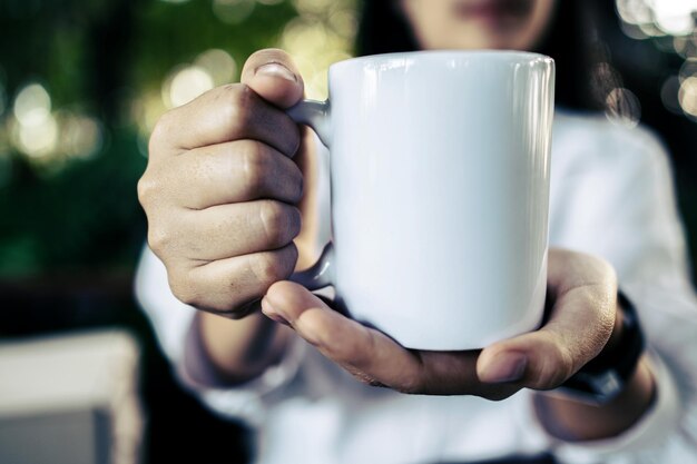 Foto taza blanca a la mano en el tiempo de relajación