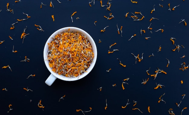 Taza blanca con pétalos de flores secas de caléndula