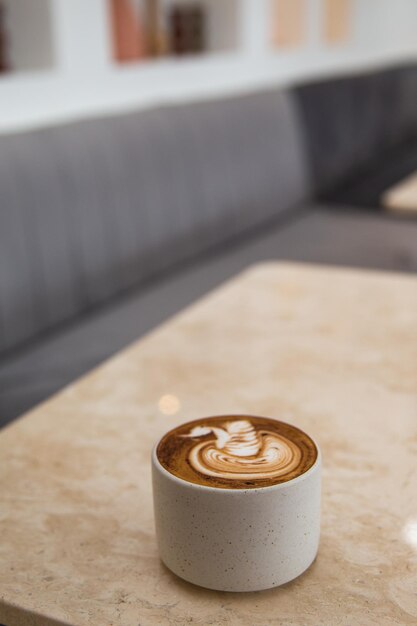 Taza blanca de sabroso capuchino con arte latte sobre fondo de mármol blanco en el café