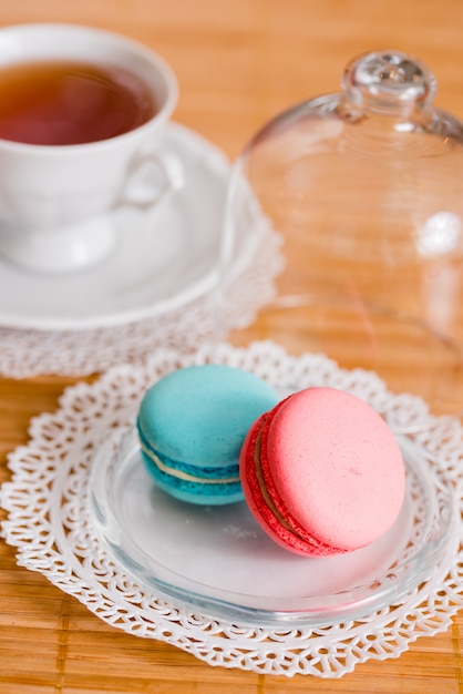 Taza blanca de té caliente, macarrones y galletas recién horneadas