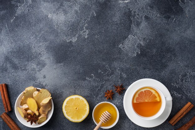 Taza blanca con té de hierbas natural jengibre limón y miel canela.