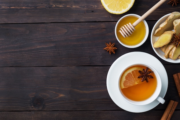 Foto taza blanca con té de hierbas natural jengibre limón y miel canela.