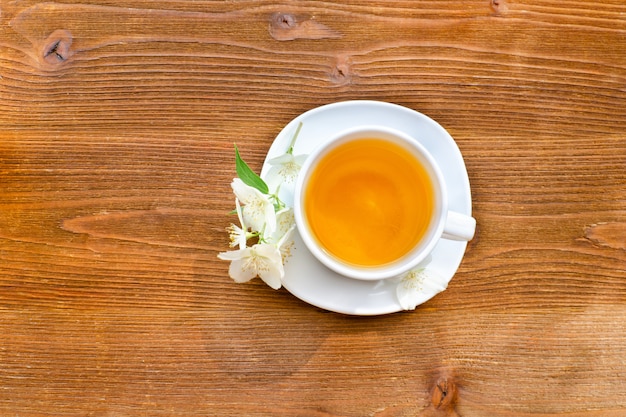 Taza blanca de té en una mesa de madera marrón.