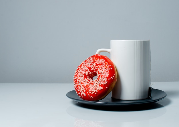 Foto taza blanca con té y una rosquilla de color dulce. concepto de trabajo desde casa