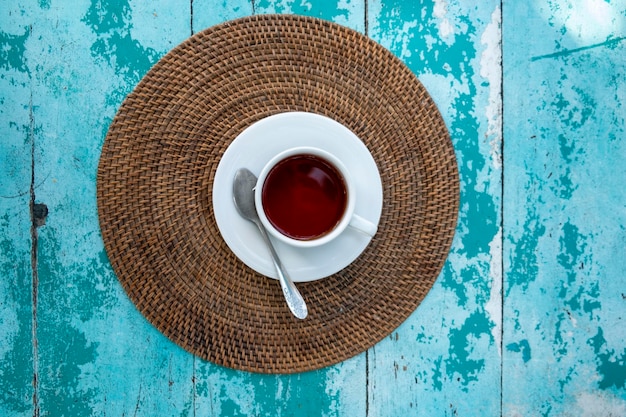 La taza blanca de té en la vieja mesa de madera vie