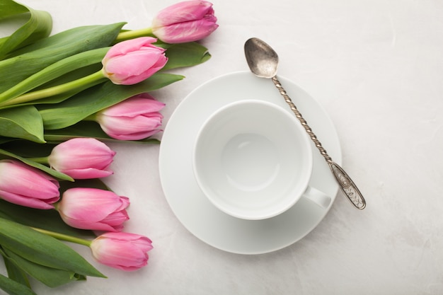 Taza blanca vacía de café y de tulipanes.