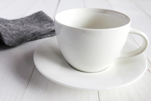 Taza blanca vacía en la mesa de madera blanca