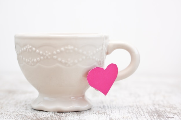 Taza con bolsita de té en forma de corazón aislado