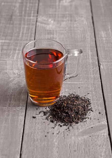 Taza de bufanda de té negro saludable y té suelto sobre superficie de madera