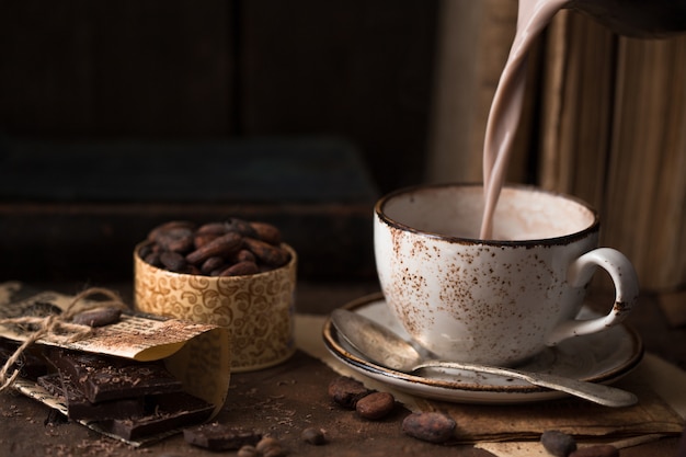 Taza de cacao aromático en mesa vieja con granos de cacao