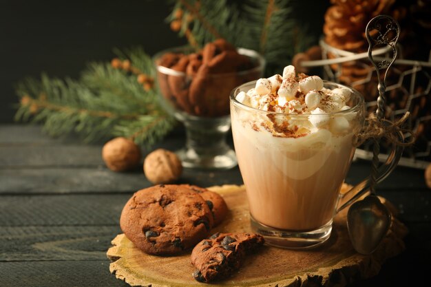 Taza de cacao caliente con malvaviscos y galletas en el cuadro negro