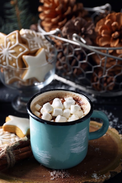 Taza de cacao caliente con malvaviscos y galletas en el cuadro negro