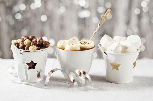 Una taza de cacao con malvaviscos y chocolate en la mesa de Navidad de Año Nuevo sobre un fondo brillante