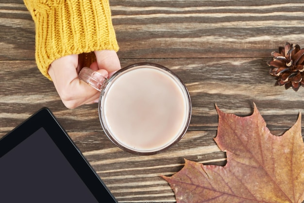 Taza de cacao y mujer mano hojas de otoño tablet pc