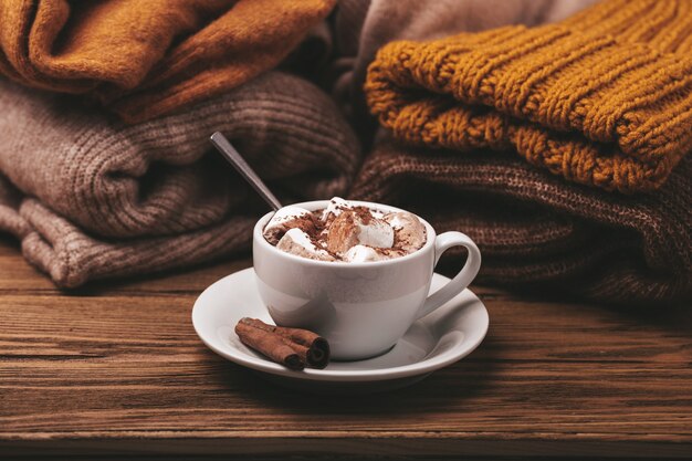 Taza de cacao y pila de géneros de punto