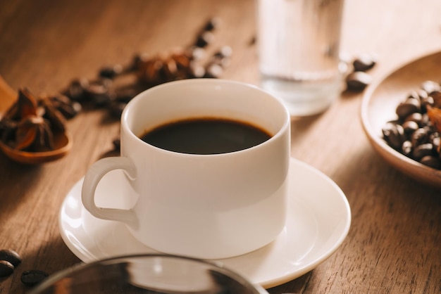Una taza de café con agua, granos de café y té en un fondo de madera