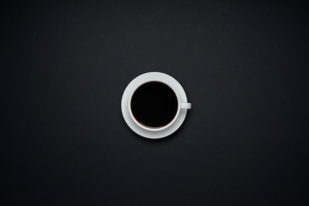 Taza de café aislada sobre fondo negro. Vista plana endecha y superior con espacio de copia.