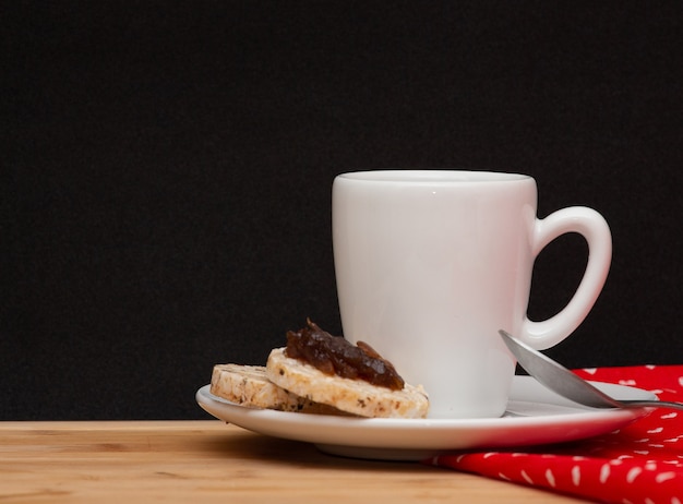 Una taza de café al lado de una cuchara y unas galletas veganas de arroz con gelatina encima