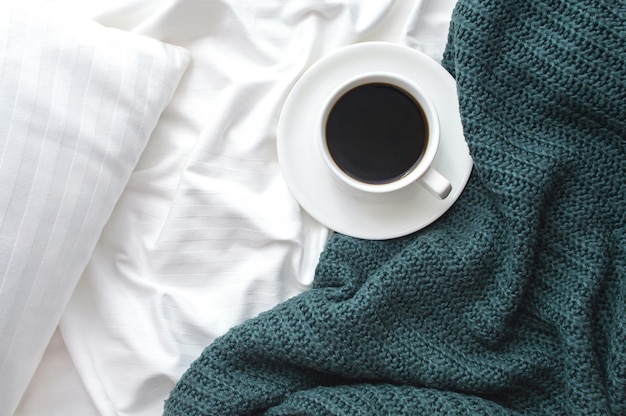 Taza de café americano en la cama con manta