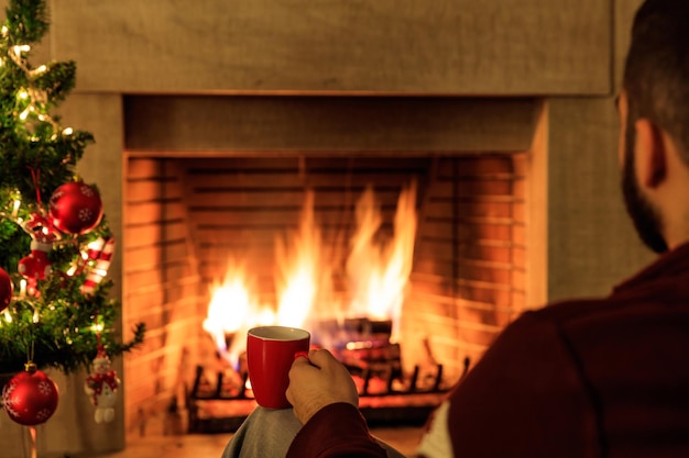 Taza de café en el árbol de Navidad y fondo de chimenea ardiente